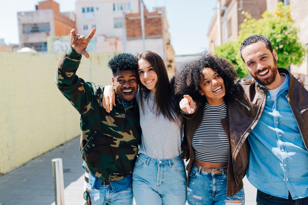 Happy stylish friends walking on urban street