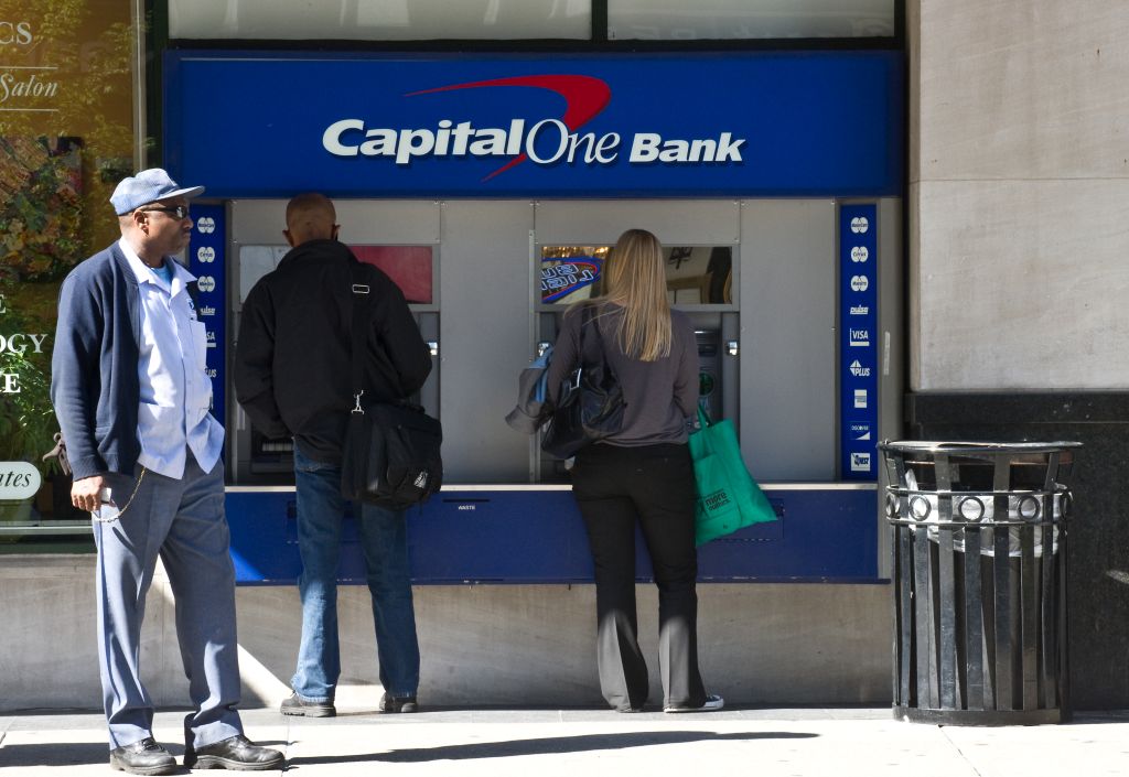 People use an ATM at a Capital One Bank