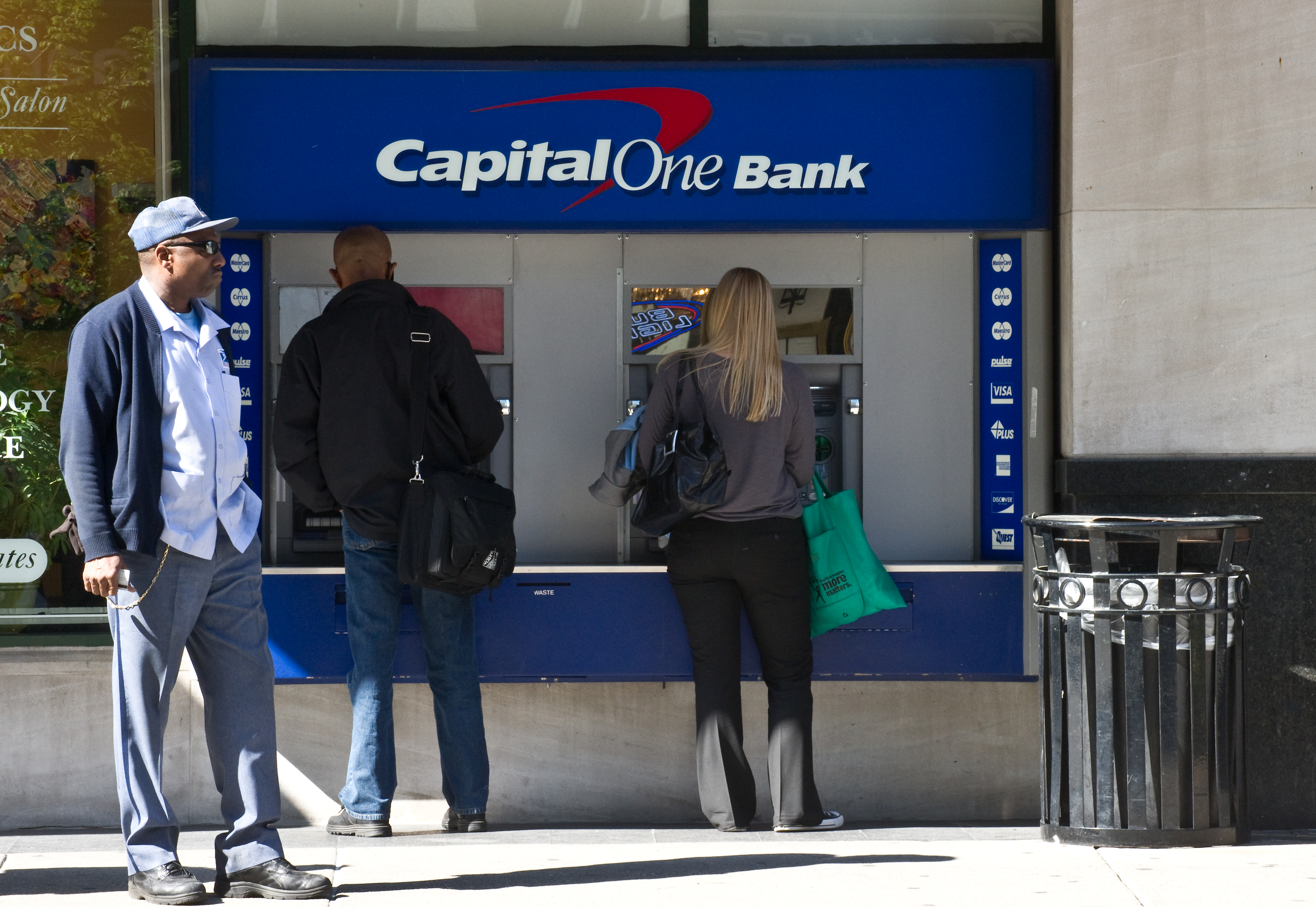 People use an ATM at a Capital One Bank