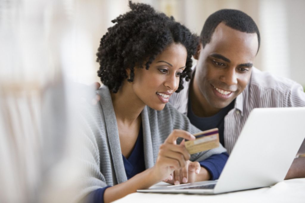 Couple holding credit card and using laptop
