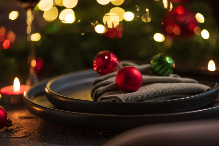 Christmas Table Setting with Tree-Shaped Napkin and Tealight Candles against Christmas lights
