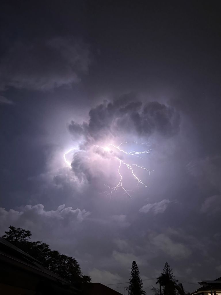 Dramatic lightning strike inside dark storm clouds at night.
