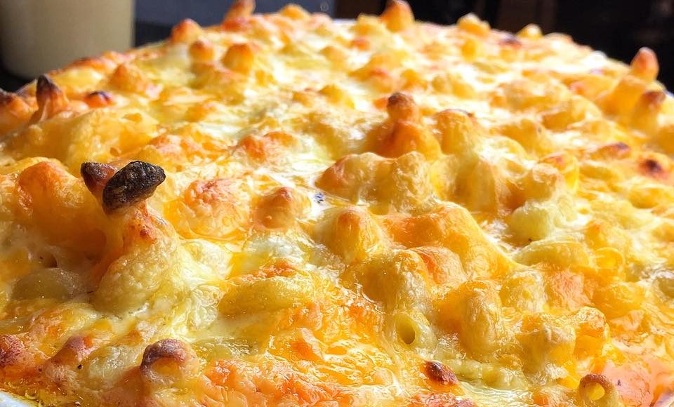 A close-up view of a baked casserole dish filled with melted cheese and golden brown pieces of bread or pastry.